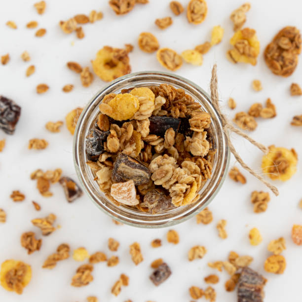 crunchy granola in glass jar isolated on white background, top view, healthy breakfast concept